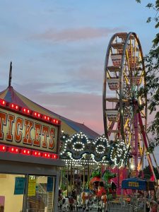 Carnival rides and Ferris wheel at the Clear Lake, Iowa July 4 celebration in City Park at sunset.