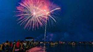 Fourth of July fireworks over Clear Lake, Iowa with families gathered on the dock and beach in downtown Clear Lake.