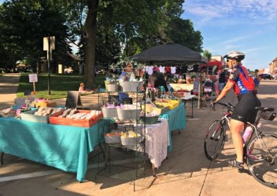 A cyclist visits a vendor booth displaying homemade soaps.