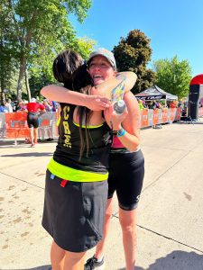 Rachel celebrating at the TRI Clear Lake finish line with a hug after completing her first triathlon in Clear Lake, Iowa.